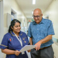 A consultant speaks with a nurse in the hospital corridor