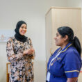 A consultant and a nurse convers in a patient's room