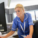 A nurse looks at the computer in reception