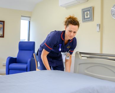 A nurse makes the bed in a private hospital room