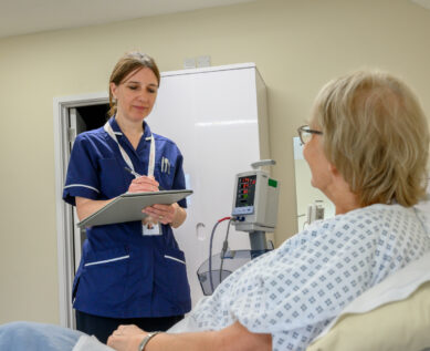 A nurse takes notes while speaking to a patient
