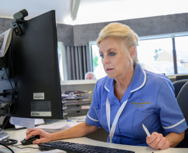 A nurse at the computer in reception
