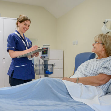 Nurse speaks with a patient in their private room