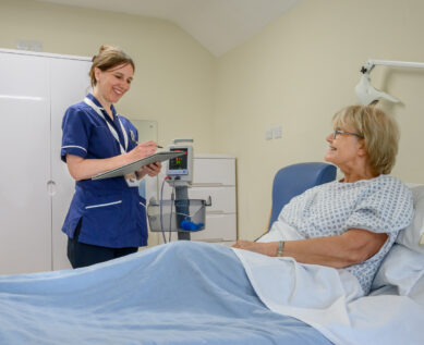 Nurse speaks with a patient in their private room