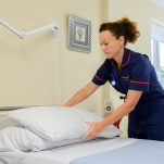 A nurse replaces pillows in a private hospital room