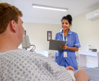 A patient speaks to a nurse in their private room